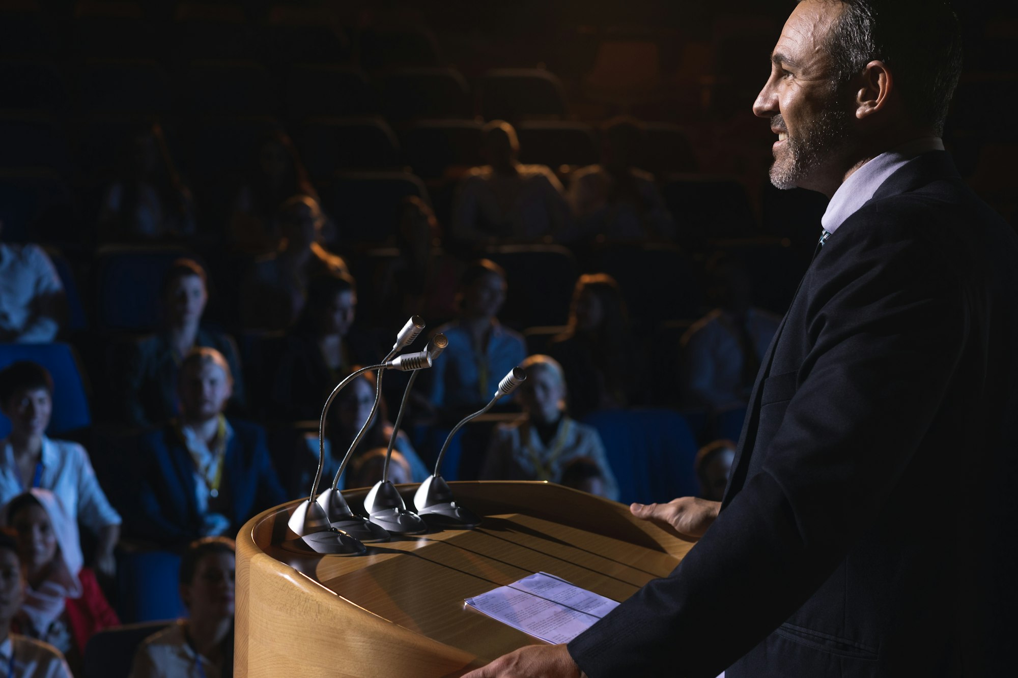 Side view of Caucasian businessman standing on a stage of auditorium for presentation